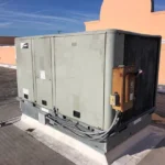Before, one of the two failed rooftop units, built in 2010 and about 16 years old, weathered and rusting at the disconnect