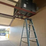 The unit hangs above an open breezeway. Just reaching it takes laddersand a crew of two
